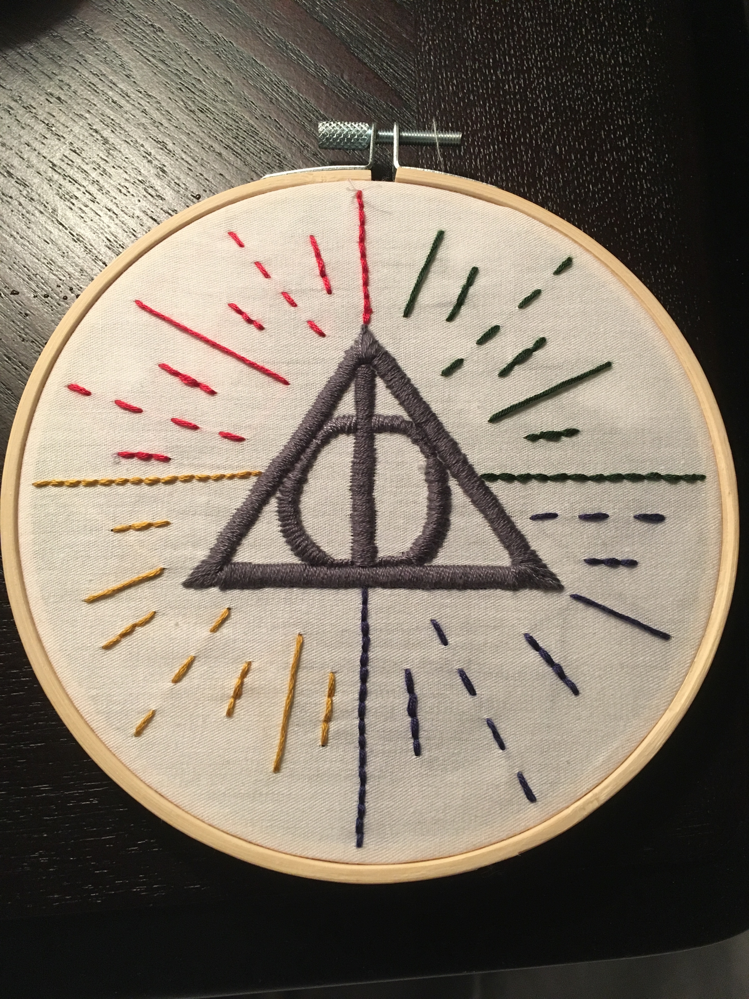 the deathly hallows triangle with red, blue, green, and yellow decorations